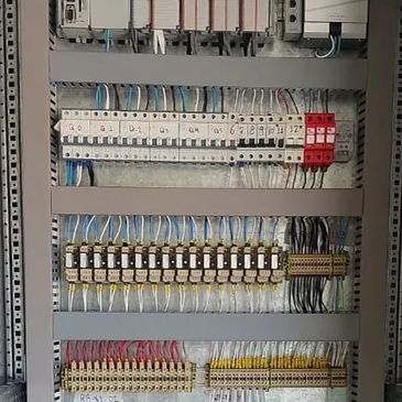 Painel elétrico organizado com fios conectados a disjuntores e relés.