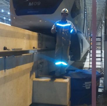 Pessoa com roupa refletiva ao lado de trem.
