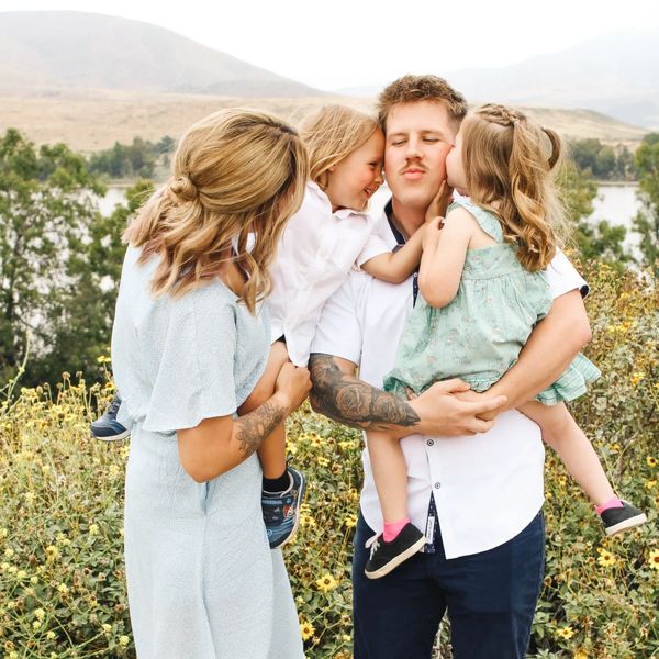 A joyful family moment with parents and children sharing kisses outdoors.