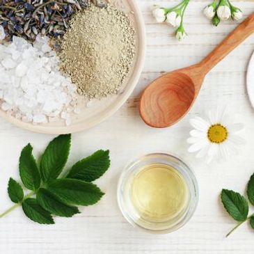 Natural spa ingredients with herbs, salt, and essential oil on a white surface.
