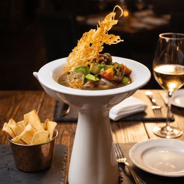 Elegant seafood dish with crispy garnish and plantain chips, paired with white wine.