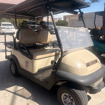 Beige Club Car golf cart parked outdoors.