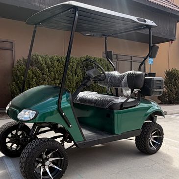 Green golf cart with lifted tires and black roof.