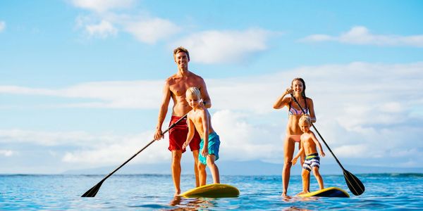Family paddleboarding together on a sunny day.