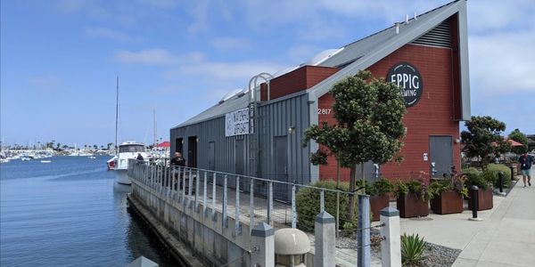 Modern waterfront building with boats docked nearby under a blue sky.