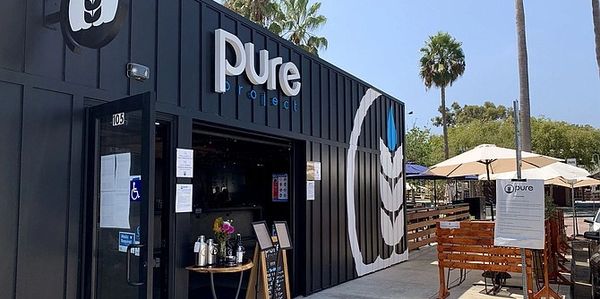 Exterior view of Pure Potage cafe with outdoor seating and palm trees.