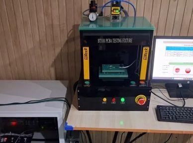 Automated PCB testing machine setup on a desk.