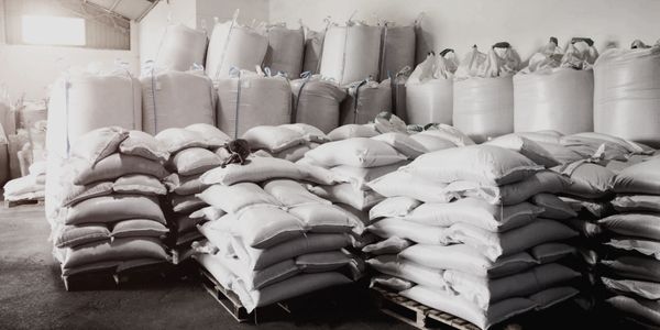 Warehouse filled with stacked large white sacks and bags on pallets.
