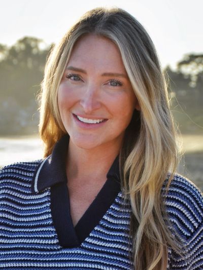 Smiling woman with long blonde hair outdoors.
