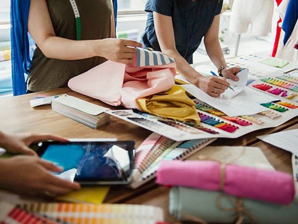Designers working with fabrics and color swatches at a workspace.