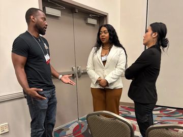 Three people having a serious conversation in a conference room.
