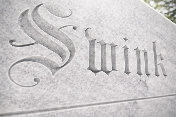 Close-up of the word 'Swink' engraved in stone.