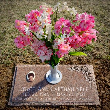 Gravestone with flowers in a vase.