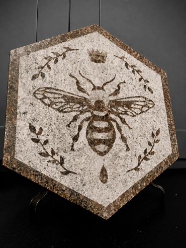 Hexagonal stone tile with a bee and crown design.