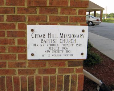 Sign for Cedar Hill Missionary Baptist Church on a brick wall.