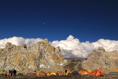 Mountain campsite with orange tents under a clear blue sky.