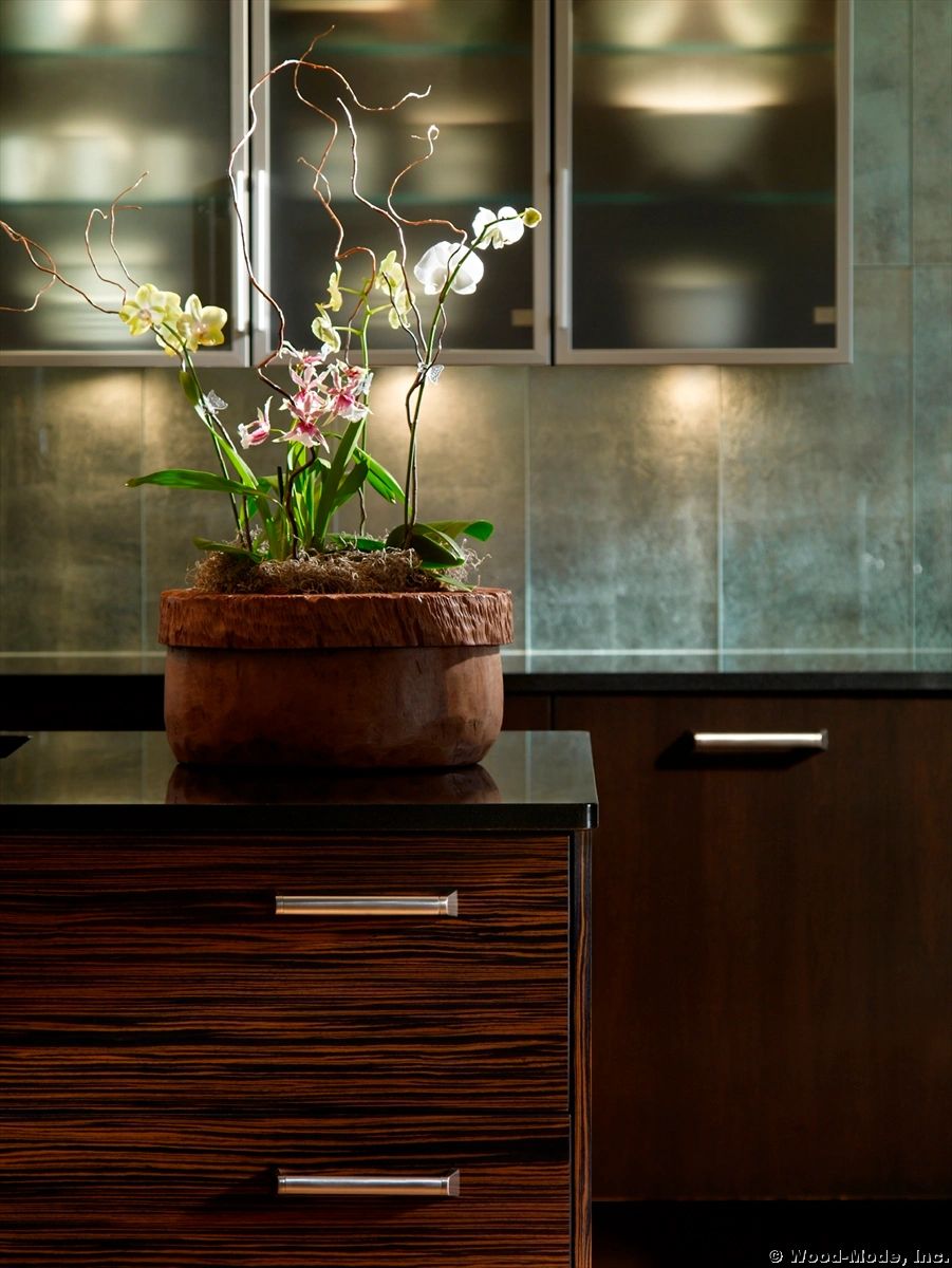 Orchid arrangement in a rustic wooden pot on a sleek kitchen island.