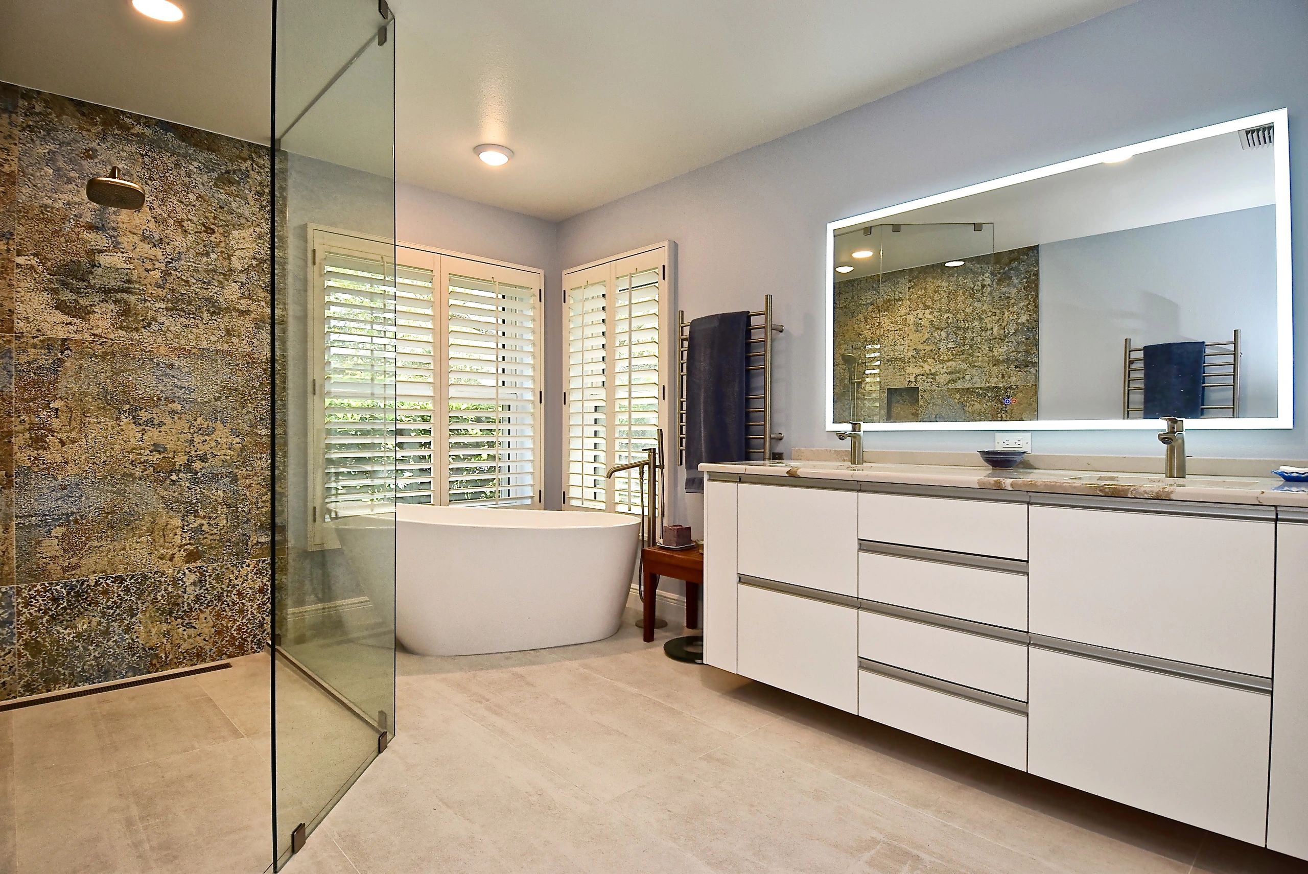 Modern bathroom with a freestanding tub, glass shower, and illuminated mirror.