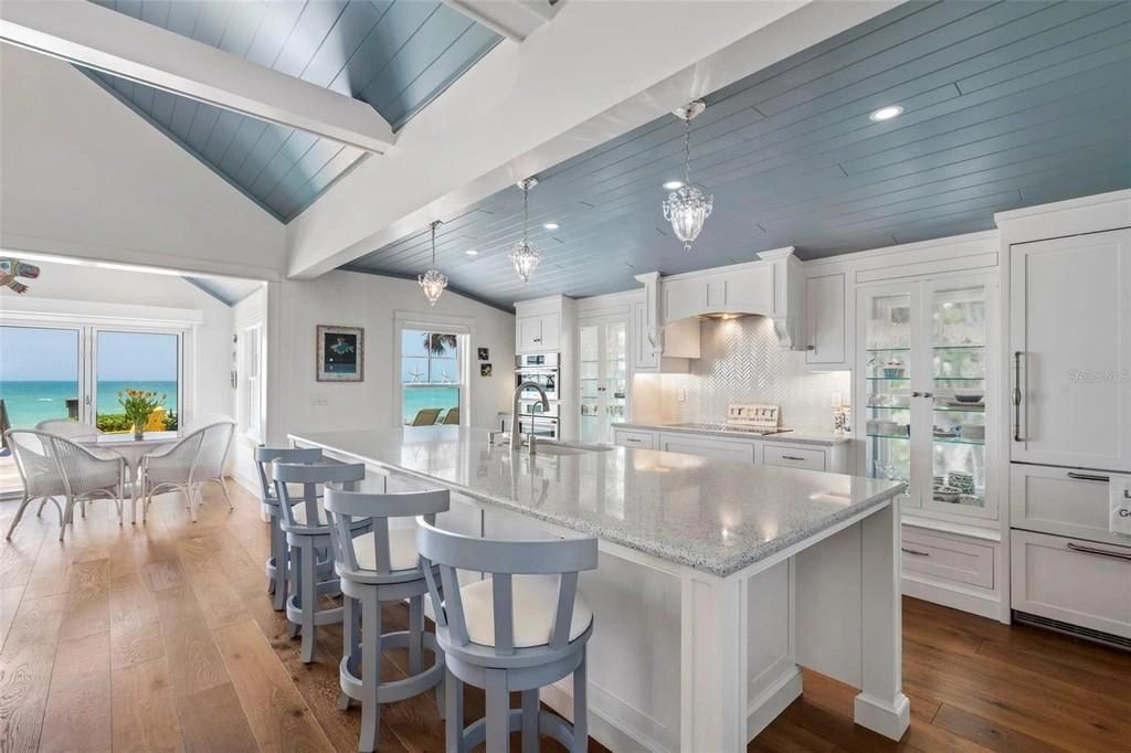 Bright coastal kitchen with blue ceiling and ocean view seating area.