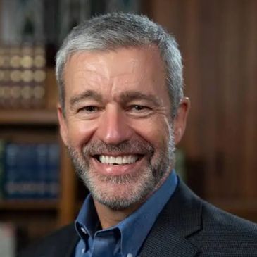 Smiling middle-aged man with gray hair and beard.