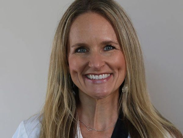 Smiling woman with long blonde hair wearing a white coat.