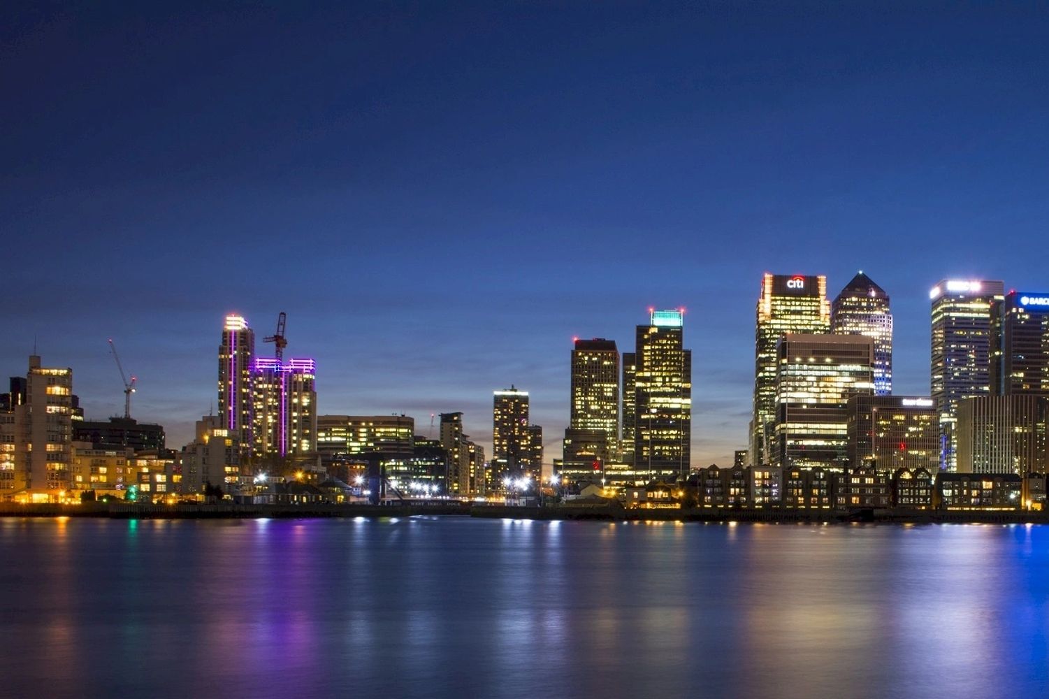 Two people shaking hands over business documents on a desk.