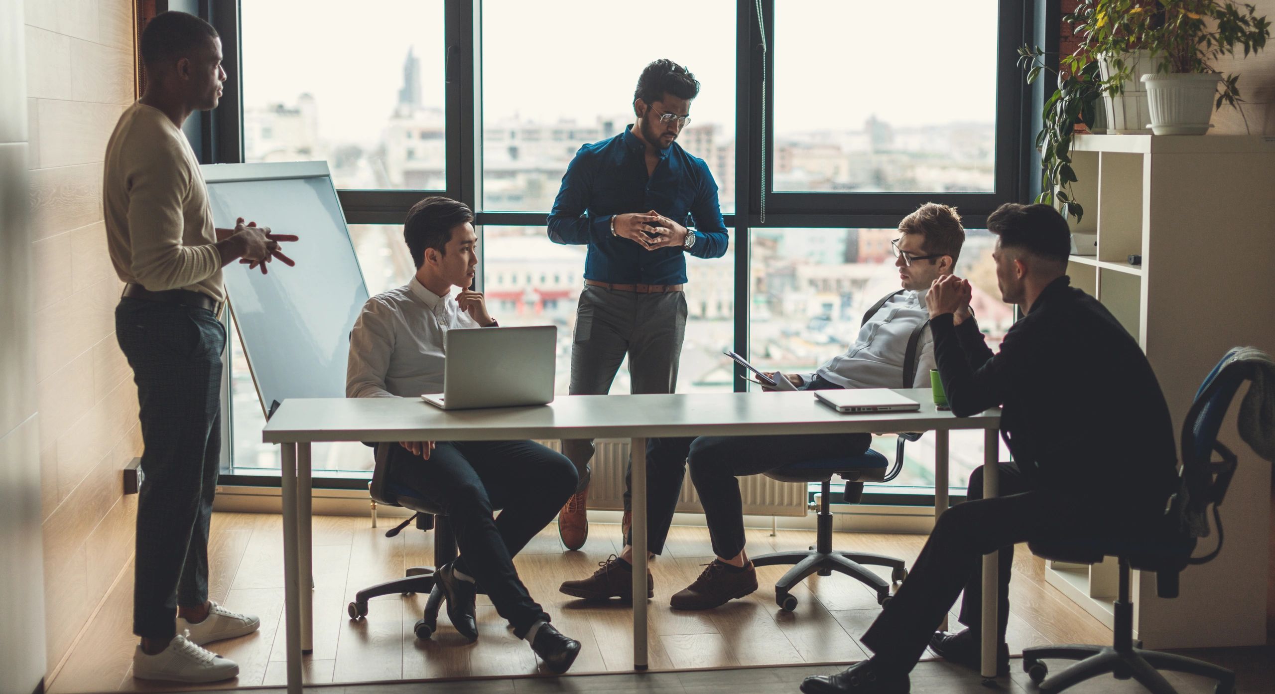 Five men in a meeting room having a discussion.