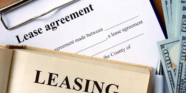 Lease agreement document with cash and a pen on a wooden table.