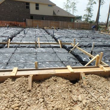 Photo of concrete forms, vapor barrier, rebar grid, and post tension cables pre-pour.