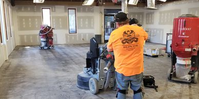 Worker operating floor polishing machine in a large room.