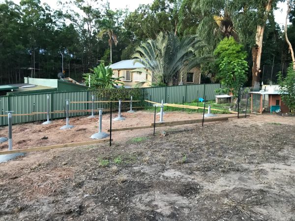 Construction site with metal posts and wooden planks in a backyard.