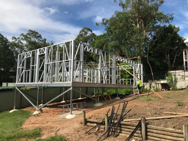 Steel frame structure of a house under construction on elevated ground.