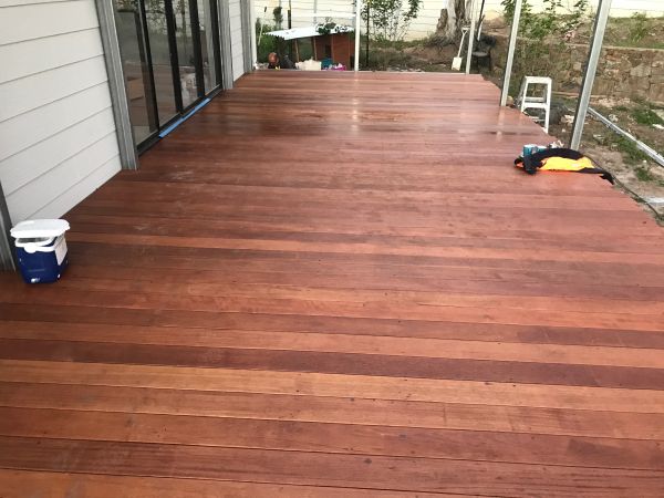 Newly installed wooden deck outside a house with minimal items around.