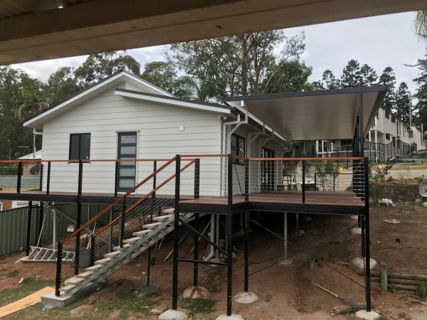Elevated modern house with a deck and stairs under construction.