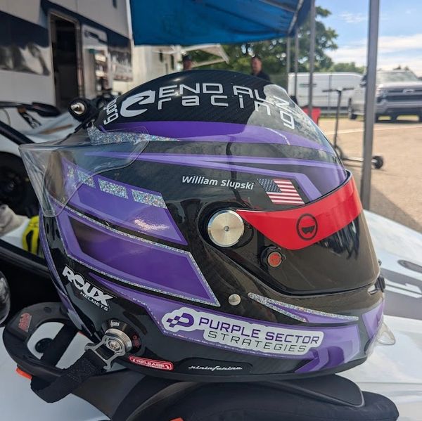 Purple racing helmet with sponsors and American flag.