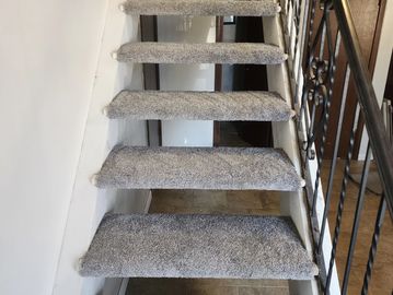 Floating carpeted stairs with a metal railing on the right side.