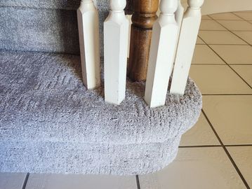 Carpeted staircase with wooden balusters and tiled floor.