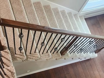 A carpeted staircase with wooden railing and metal rods brown wood floor. Installed Kansas City MO