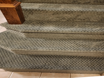Carpeted stairs with a diamond pattern and wooden banister post.