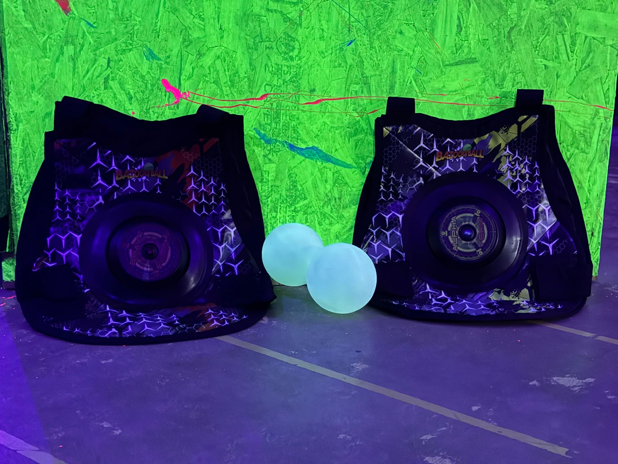 Two black speaker boxes with glowing blue balloons and neon green wall.