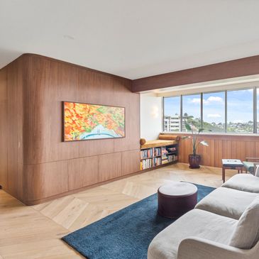 Bright living room with large windows and wooden paneling.