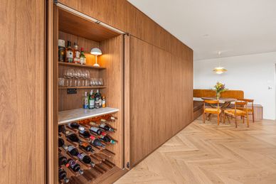 Hidden wooden cabinet with wine and liquor bottles.