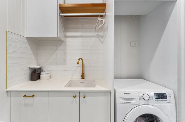 Modern laundry area with white cabinets and laundry machine.