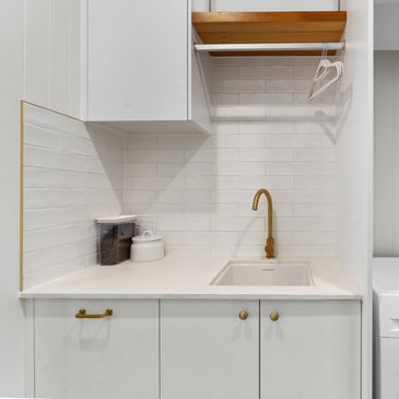 Modern laundry area with white cabinets and laundry machine.