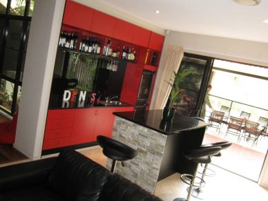 Modern kitchen with red cabinets and bar stools.