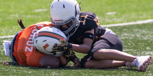 Two young football players collide on the field during a game.
