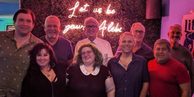 Group photo with neon sign "Let us be your Alibi".