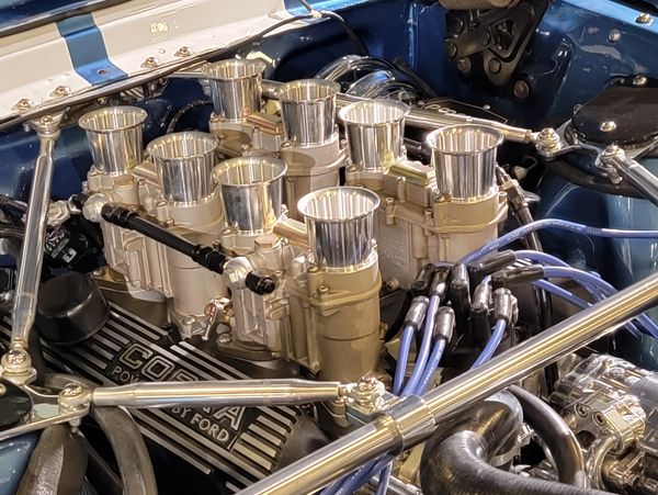 Close-up of a classic Cobra Ford engine with polished carburetors.