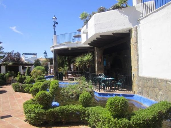 A terrace with water on the sides and decorative bushes