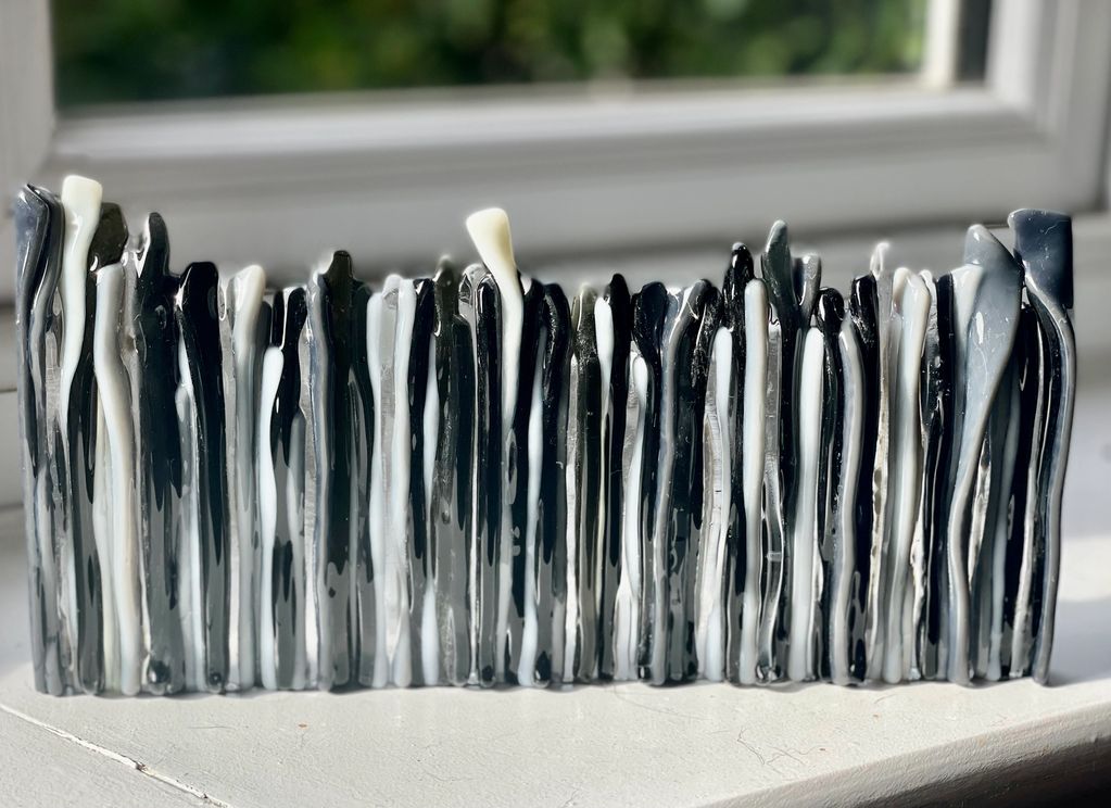 A textured piece of decorative glass art in greys, blacks and white